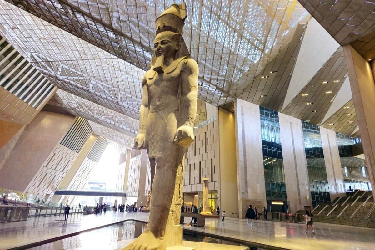 Grand Egyptian Museum: Entry Ticket + Hotel Transfers + Nile Dinner Cruise A large statue of an ancient Egyptian figure stands in a modern indoor space with a high ceiling and glass walls.