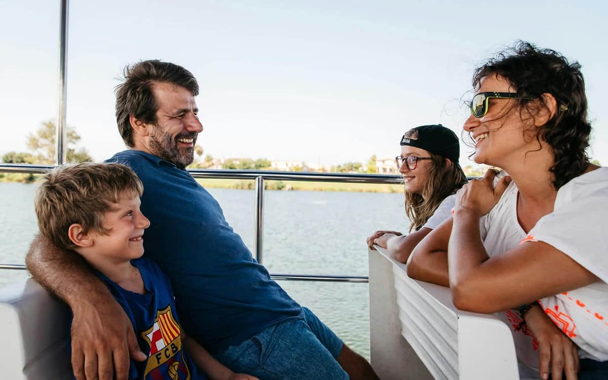 River Cruise on the Ebro Delta Four people smiling and laughing on a boat ride, with water and greenery in the background.