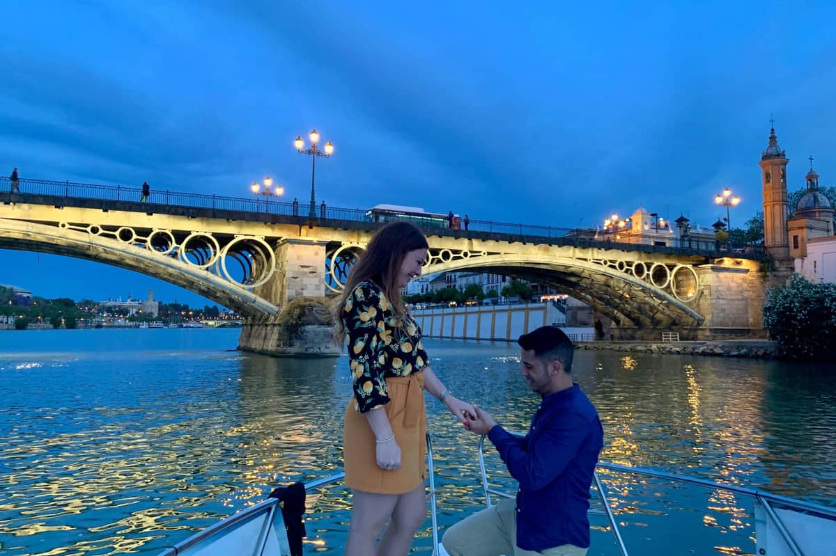 Séville : 1 heure d'excursion romantique en bateau Un couple sur le bateau avec le pont Isabel II en arrière-plan