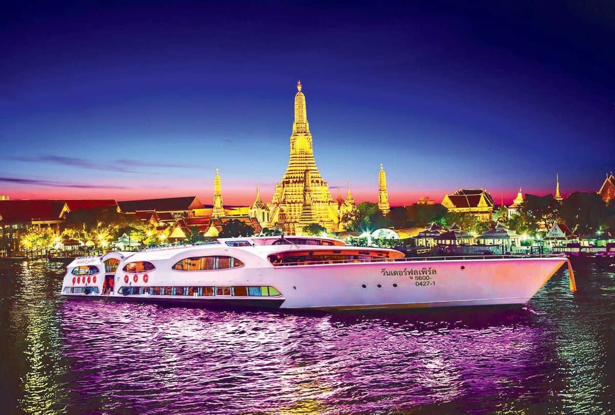 Ayutthaya: Grand Pearl River Cruise Tour + Buffet From Bangkok Illuminated white boat on a river with a backdrop of a brightly lit temple and cityscape at dusk.