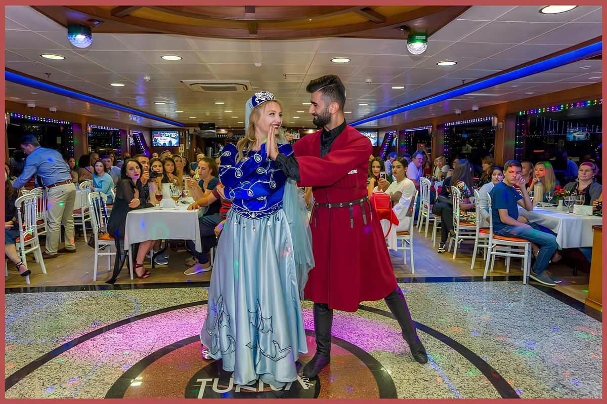 Istanbul: 4-Hr Bosphorus Dinner Cruise with Ottoman Dance Show A man and woman, both in medieval costumes, dance on a boat. People sit at tables in the background, watching them.